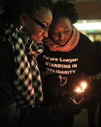 Two women lighting a candle at the Ferguson Solidarity Vigil