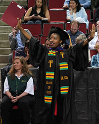 A graduate with her arms raised at the 2018 Commencement Ceremony